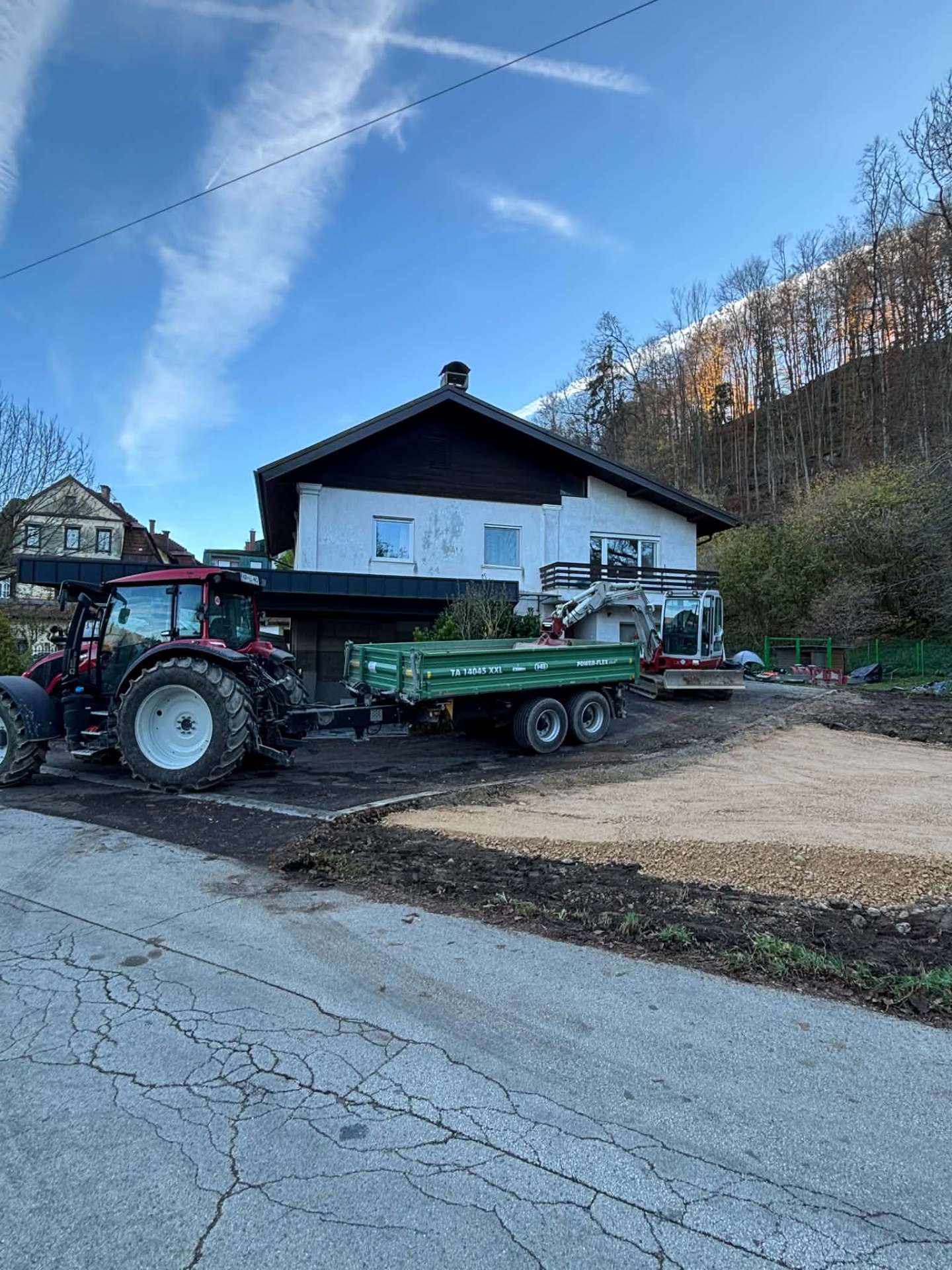 Traktor s prikolico in bager pri pripravi dvorišča